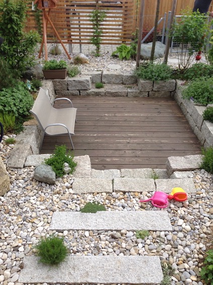 Die extrem kleine Gartenfl&auml;che wurde mit einem Holzdeck am Haus, einem kleinen versenkten Sitzplatz im hinteren Bereich sowie einer Bepflanzung mit Geh&ouml;lzen und Stauden in Kiesbeeten sehr abwechslungsreich. (Poing bei M&uuml;nchen)