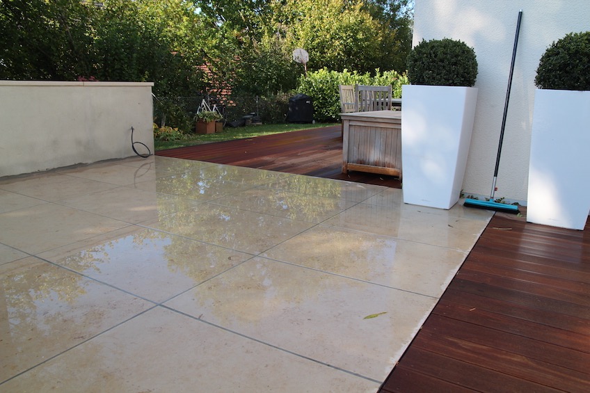 Der Loungebereich aus gro&szlig;formatigen Kalksteinplatten verbindet zwei Holzdecks aus Bangkirai.  (Unterschlei&szlig;heim)