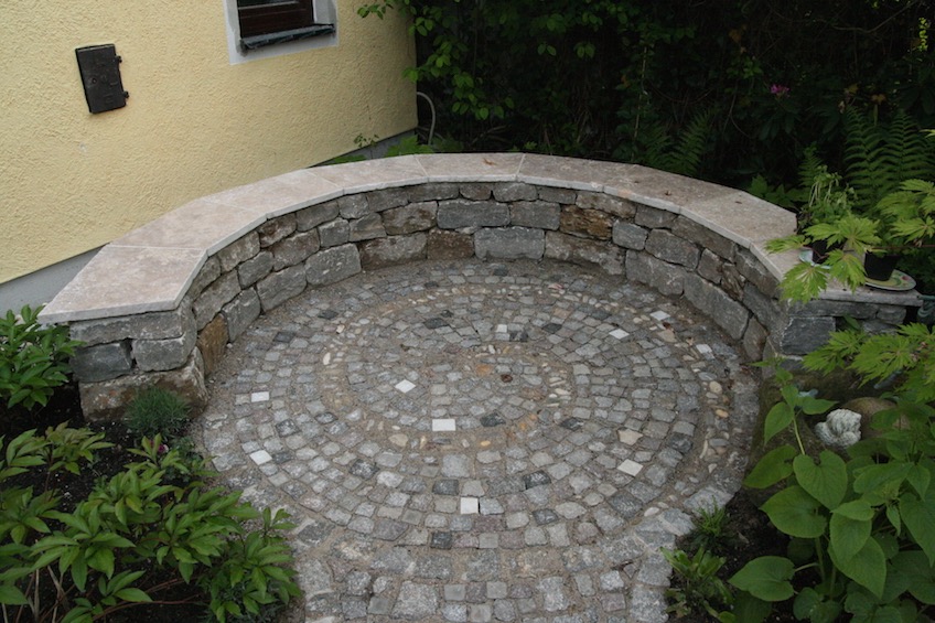 Sitzmauer aus Muschelkalk Mauersteinen, Belag mit eingepflasterter Schnecke aus Bummerln. (Freising)