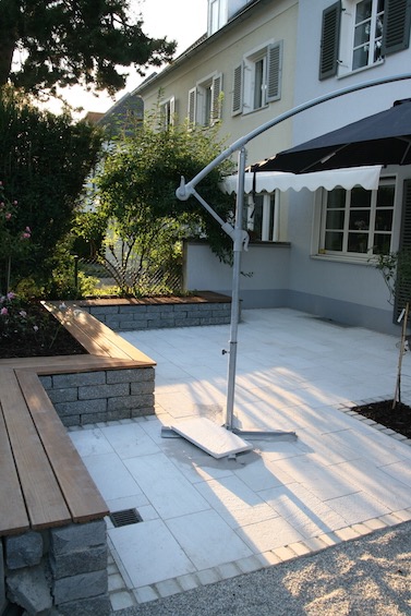 Lounge Terrasse mit Sitzmauer aus dunklem Granit, Holzauflage aus Bangkirai und Belag aus Rauriser Marmor. (M&uuml;nchen)