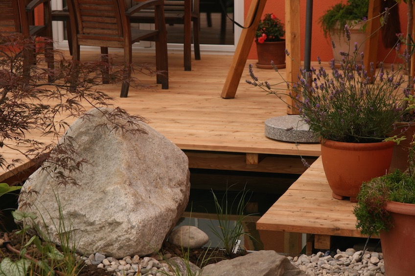 Holzdeck mit angrenzender Wasserfl&auml;che und Findling. (Poing bei M&uuml;nchen)