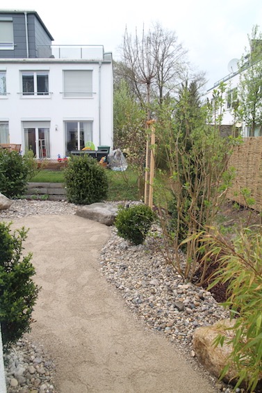 Weg aus wassergebundener Decke mit Kiesbeeten. Bepflanzung  mit Bambus, Buchs, Flieger, Kirschlorbeer und Stauden. (Freising)