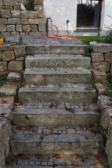 Treppe mit gebrauchten Granit Randsteinen. Auftritte ausgepflastert mit gebrauchtem Granit Kleinstein und Mosaik. Mauereinfassung aus Muschelkalk.  (Attenkirchen bei Freising)