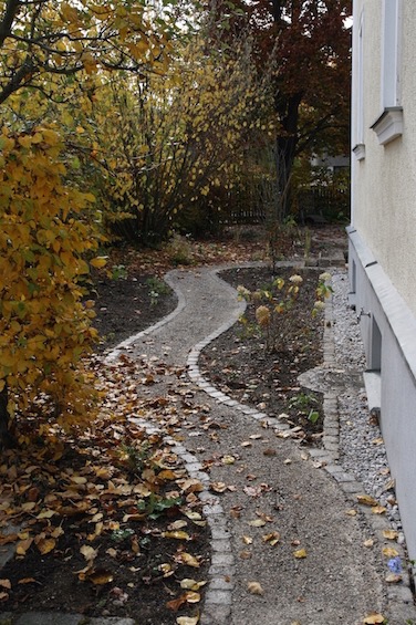 Geschwungener Weg mit Einfassung aus gebrauchtem Granit, befestigt mit wassergebundener Decke. (München)