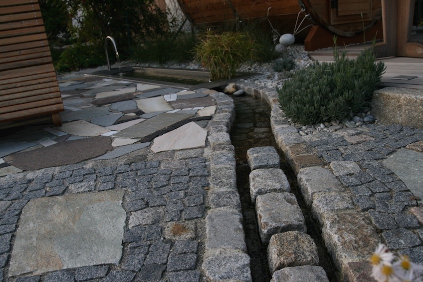 An der Stelle wo der Bachlauf den Gartenweg kreuzt, fliesst er zwischen einer Reihe Granit Großstein hindurch, um das Laufen zu erleichtern. (Mauern bei Moosburg)
